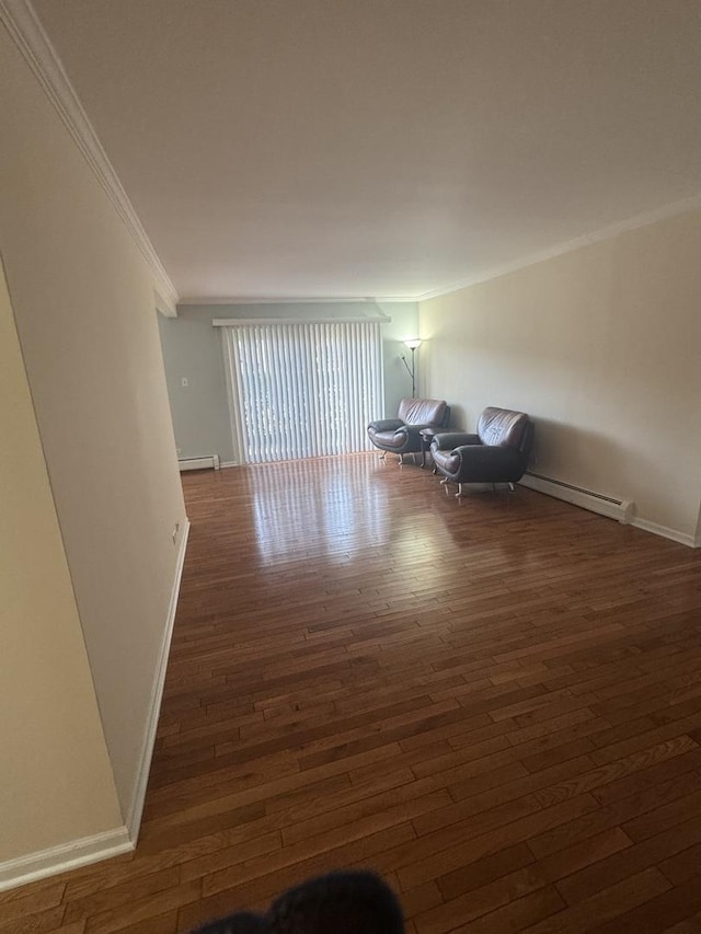 interior space featuring baseboard heating, baseboards, wood-type flooring, and ornamental molding