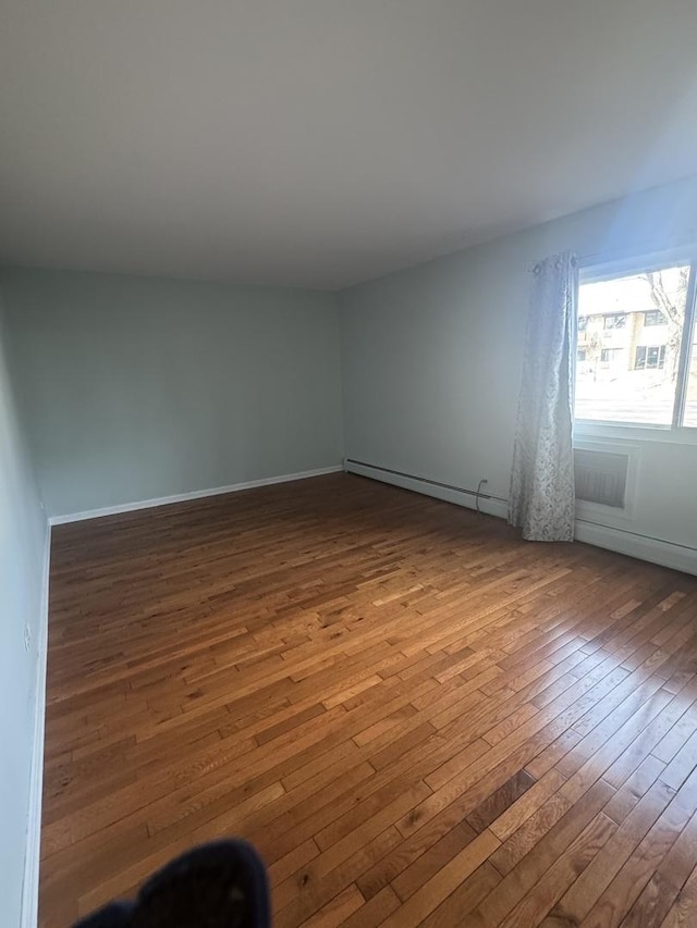 spare room with baseboard heating and hardwood / wood-style floors