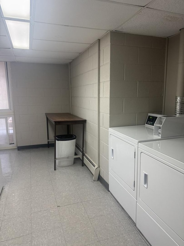 laundry room featuring washing machine and clothes dryer, a baseboard heating unit, and concrete block wall