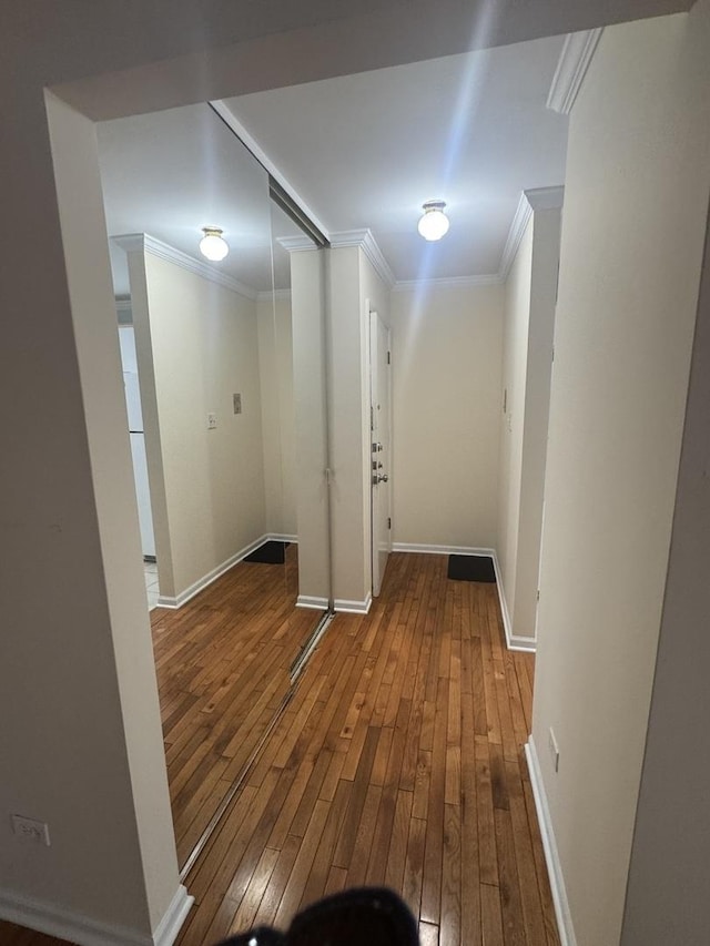 hall featuring hardwood / wood-style flooring, baseboards, and ornamental molding