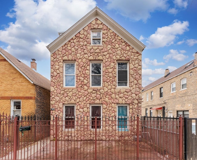 rear view of property featuring stone siding and a fenced front yard