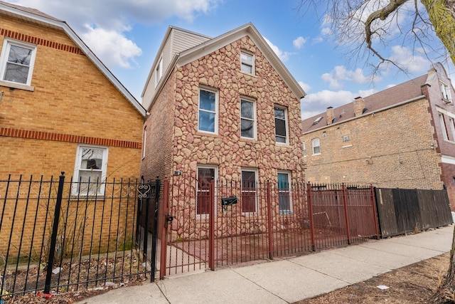 view of front of home with a fenced front yard and stone siding