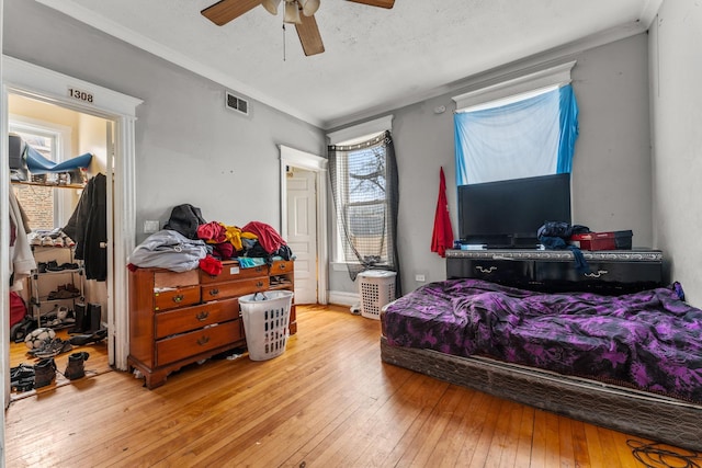 bedroom with visible vents, crown molding, a ceiling fan, and wood-type flooring