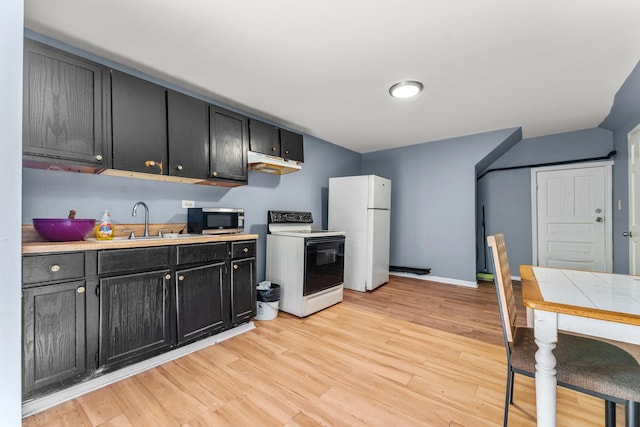 kitchen featuring light wood finished floors, a sink, light countertops, white appliances, and dark cabinets