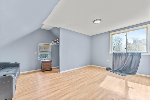 interior space featuring vaulted ceiling, light wood-style floors, baseboards, and a wealth of natural light