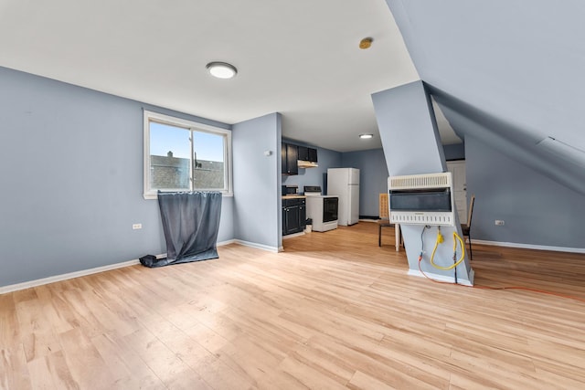 unfurnished living room featuring light wood finished floors, heating unit, lofted ceiling, and baseboards