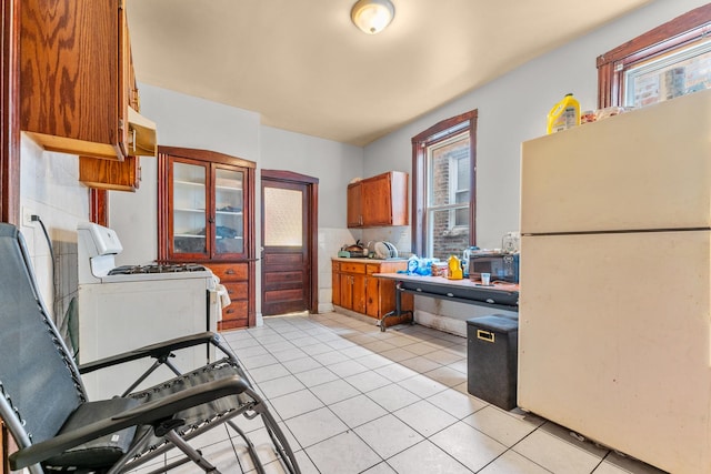 kitchen with light tile patterned floors, white appliances, light countertops, and brown cabinetry