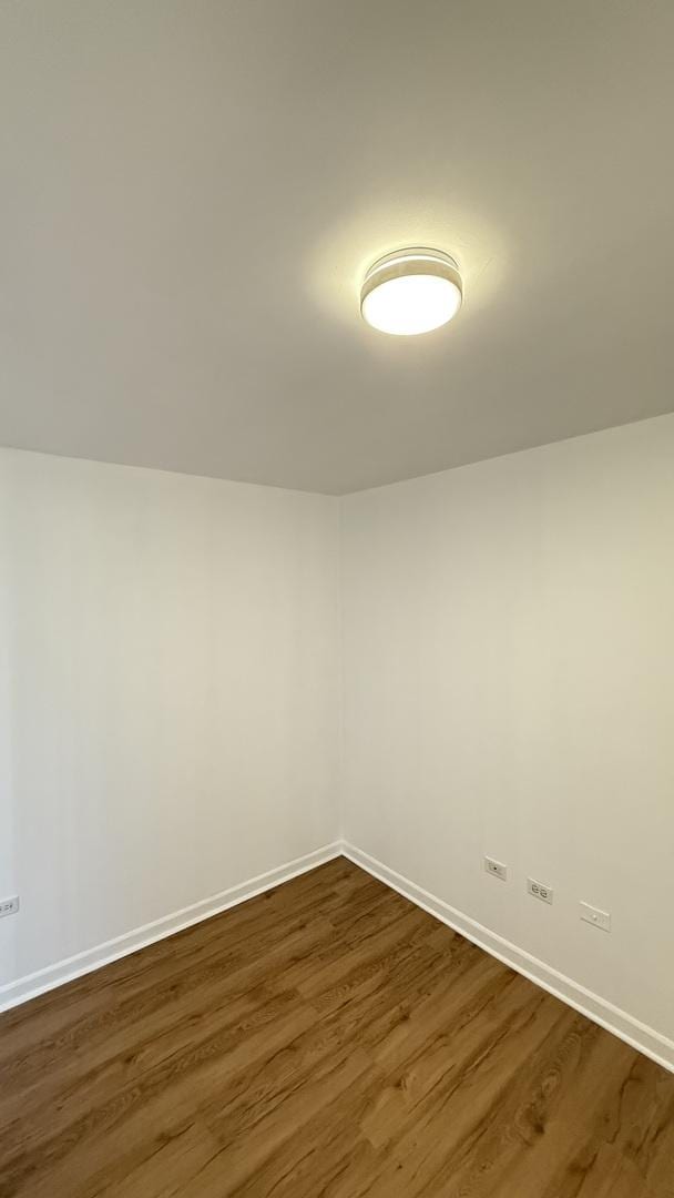 spare room with dark wood-type flooring and baseboards