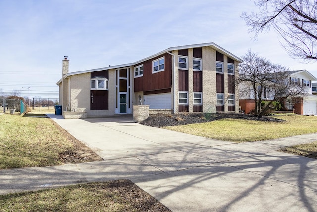 mid-century inspired home with driveway, a chimney, a front lawn, a garage, and brick siding