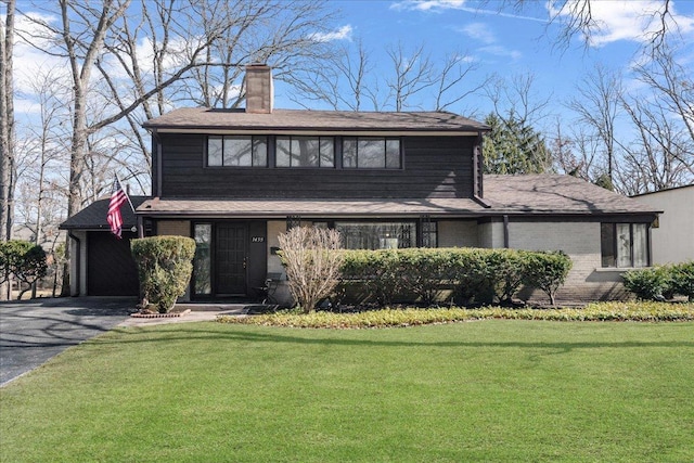 view of front of home featuring brick siding, a front lawn, aphalt driveway, a chimney, and a garage