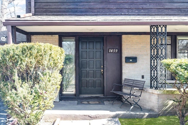 doorway to property with brick siding and a porch