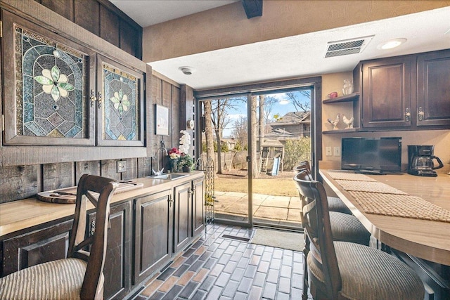 home office featuring brick floor, visible vents, and a sink