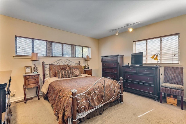 bedroom with track lighting, light colored carpet, and baseboards