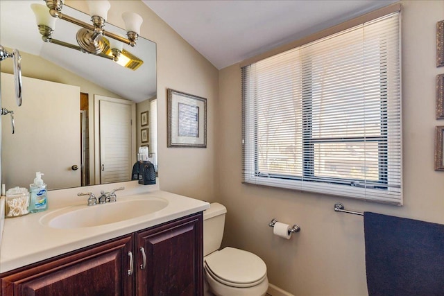 bathroom featuring toilet, vanity, and vaulted ceiling