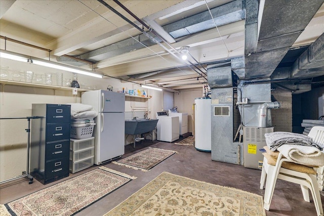 unfinished below grade area featuring water heater, washing machine and dryer, freestanding refrigerator, and a sink