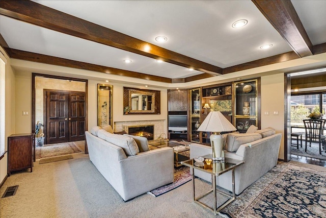 carpeted living room with visible vents, beam ceiling, and a glass covered fireplace