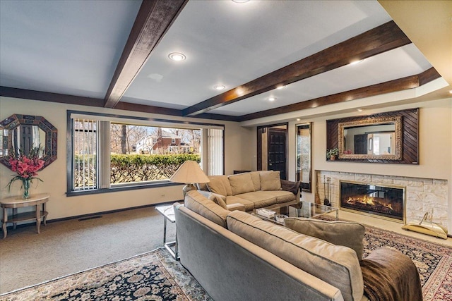 carpeted living area with a glass covered fireplace, beamed ceiling, visible vents, and baseboards