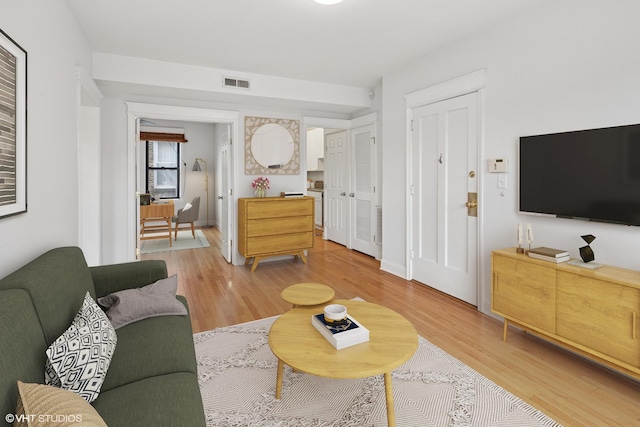 living area featuring light wood-style flooring, baseboards, and visible vents