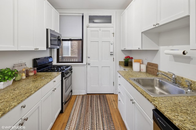 kitchen with white cabinetry, light wood-style flooring, appliances with stainless steel finishes, and a sink