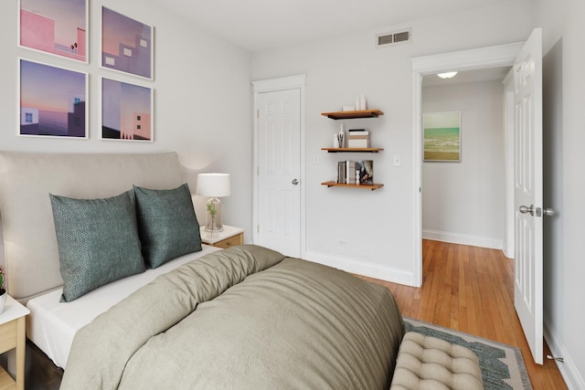 bedroom with visible vents, baseboards, and wood finished floors