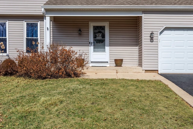 view of exterior entry featuring a yard, a garage, and a shingled roof