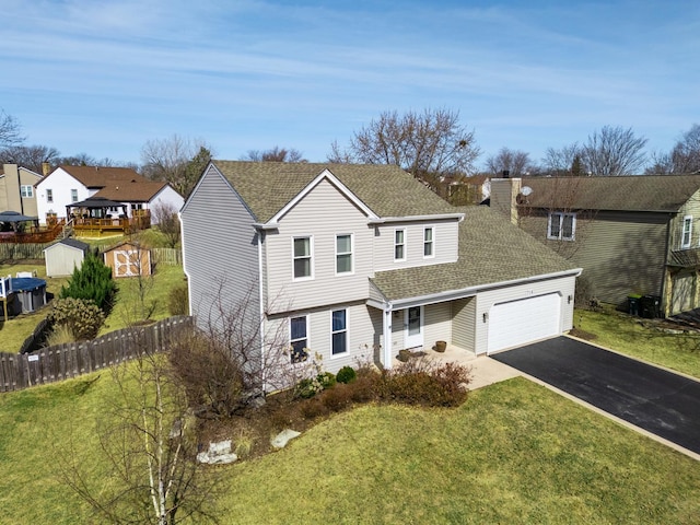 view of front of house with a front yard, fence, roof with shingles, an attached garage, and aphalt driveway