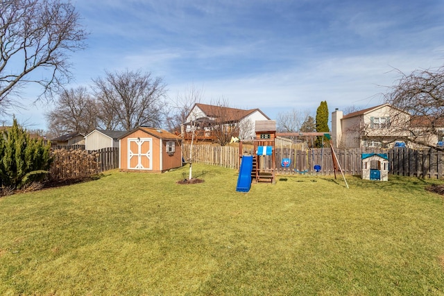 view of yard with an outbuilding, a storage shed, a fenced backyard, and a playground