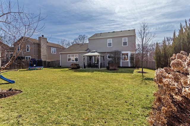 back of property featuring fence, a yard, a gazebo, a playground, and a trampoline