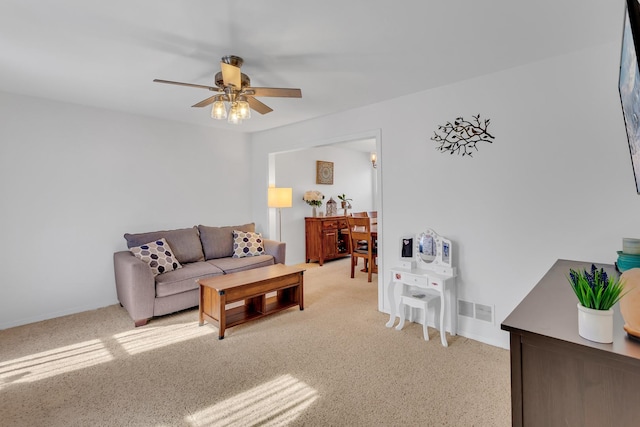 living room with a ceiling fan, visible vents, and light carpet