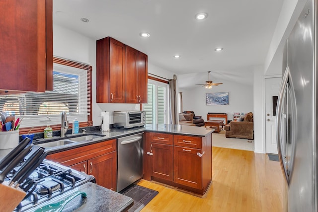 kitchen featuring light wood-style flooring, a toaster, a sink, appliances with stainless steel finishes, and open floor plan