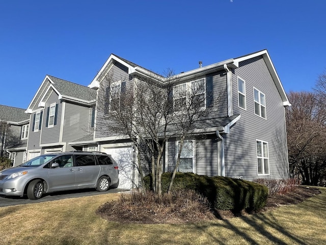 view of front of home featuring an attached garage, concrete driveway, and a front yard