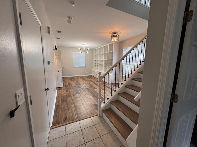 entryway with visible vents, baseboards, an inviting chandelier, tile patterned flooring, and stairs