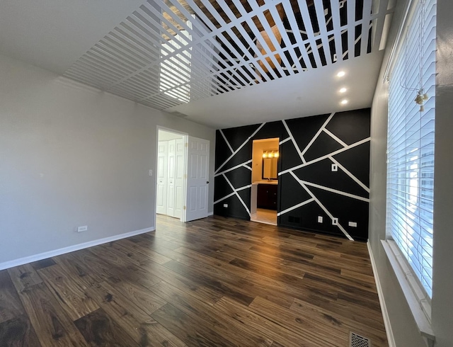 unfurnished room with visible vents, dark wood-style flooring, and baseboards