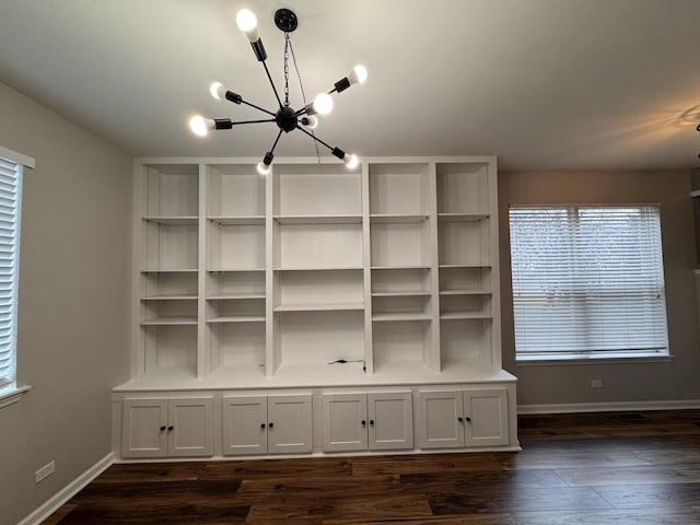 details featuring an inviting chandelier, baseboards, and wood finished floors