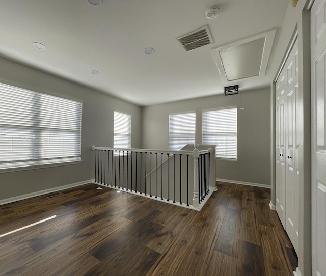 hall with visible vents, baseboards, attic access, an upstairs landing, and wood-type flooring