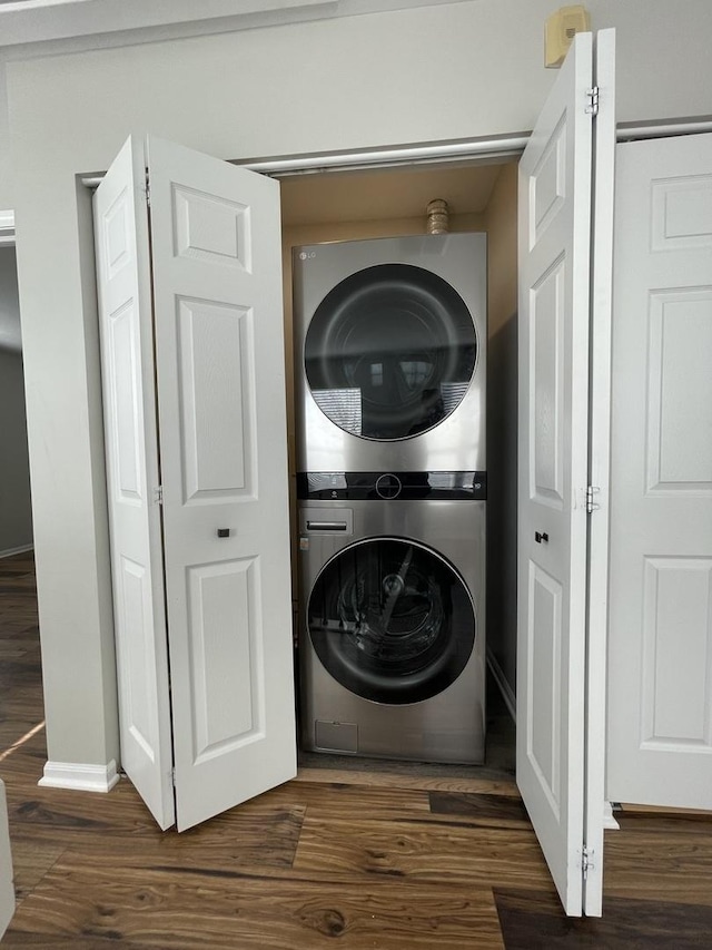 laundry area with laundry area, stacked washer and clothes dryer, baseboards, and wood finished floors