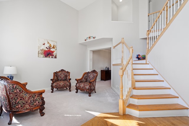 stairway with baseboards, a high ceiling, and carpet