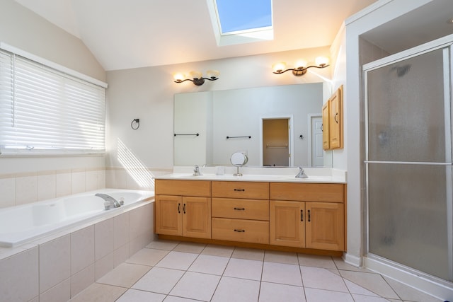 bathroom with tile patterned flooring, vaulted ceiling with skylight, a shower stall, and a sink