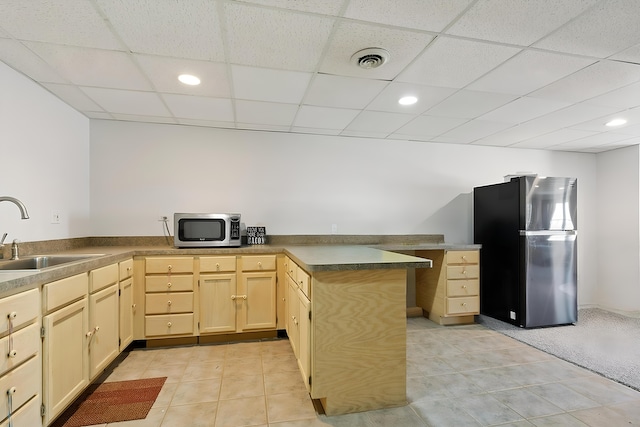 kitchen with visible vents, light brown cabinets, a peninsula, stainless steel appliances, and a sink