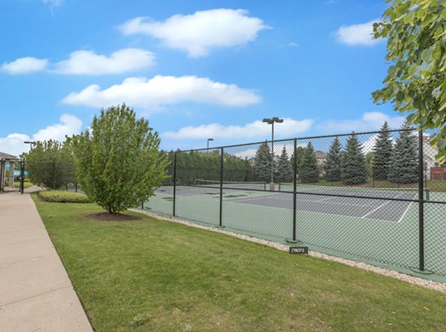 view of sport court with a lawn and fence