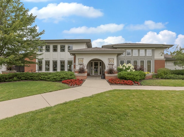 view of front of property featuring a front lawn, french doors, brick siding, and stucco siding