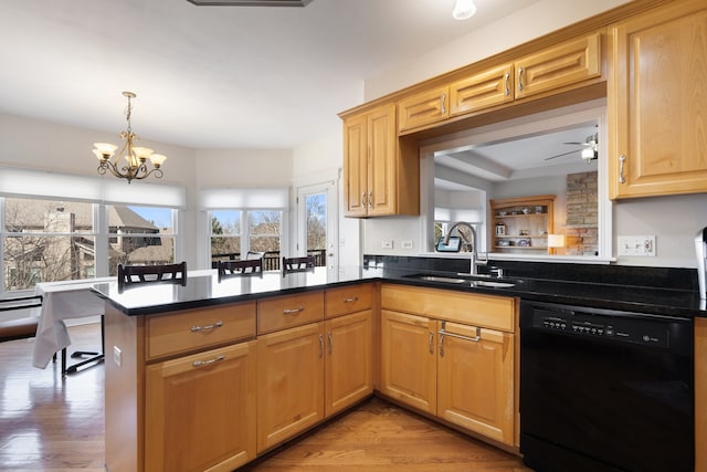 kitchen with light wood finished floors, a peninsula, a sink, hanging light fixtures, and dishwasher