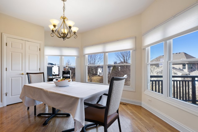 dining space with light wood-type flooring, baseboards, a notable chandelier, and visible vents