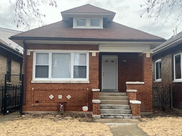 bungalow with entry steps, fence, and brick siding