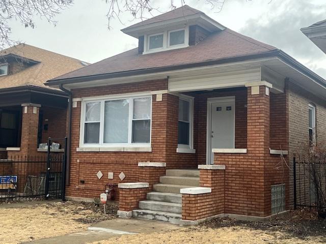 bungalow-style home with fence and brick siding