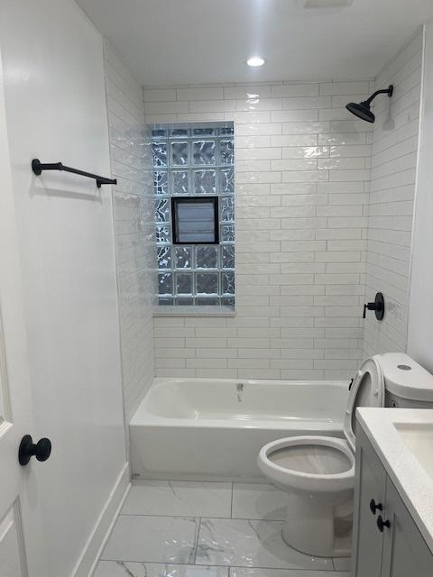 full bath with vanity, shower / tub combination, toilet, and marble finish floor