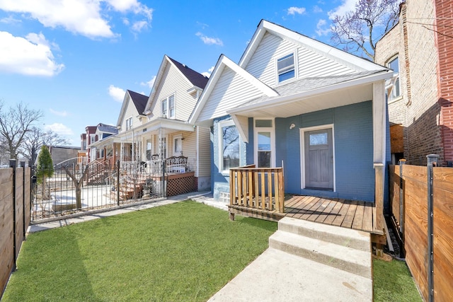 view of front of home with brick siding, a front lawn, fence, a residential view, and a porch