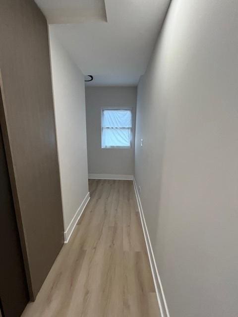 hall with baseboards and light wood-type flooring