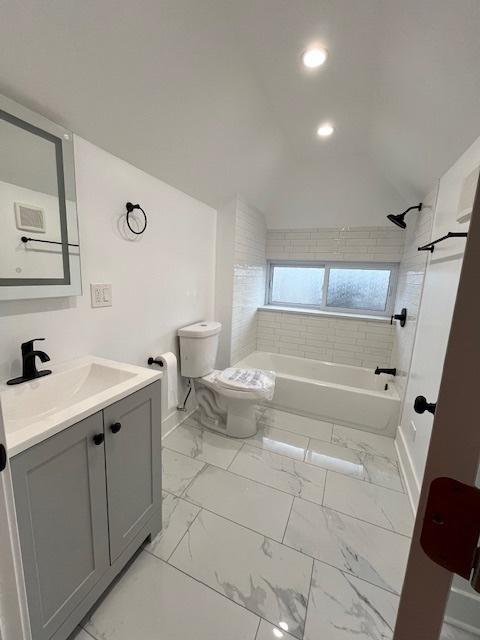 full bathroom with washtub / shower combination, vanity, toilet, marble finish floor, and baseboards
