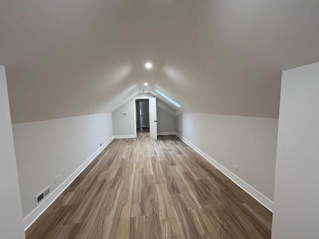 bonus room with visible vents, baseboards, recessed lighting, vaulted ceiling, and wood finished floors